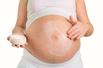 kvinde smoerer hendes gravide mave i lotion